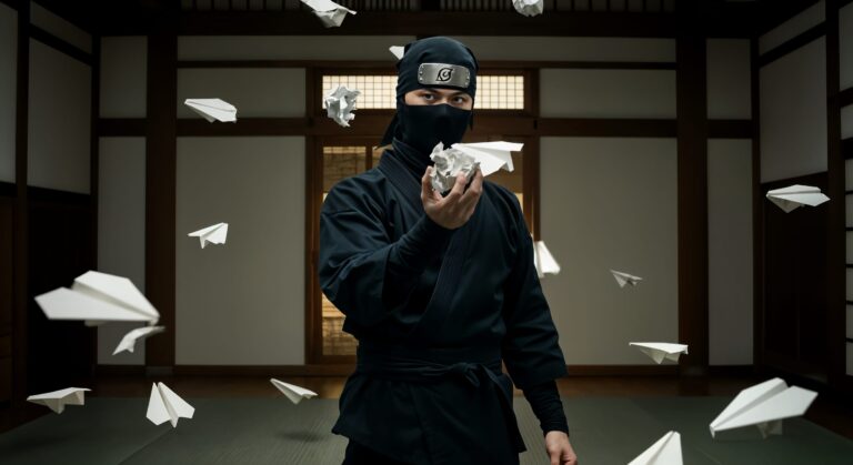 Ninja surrounded by flying paper planes indoors.