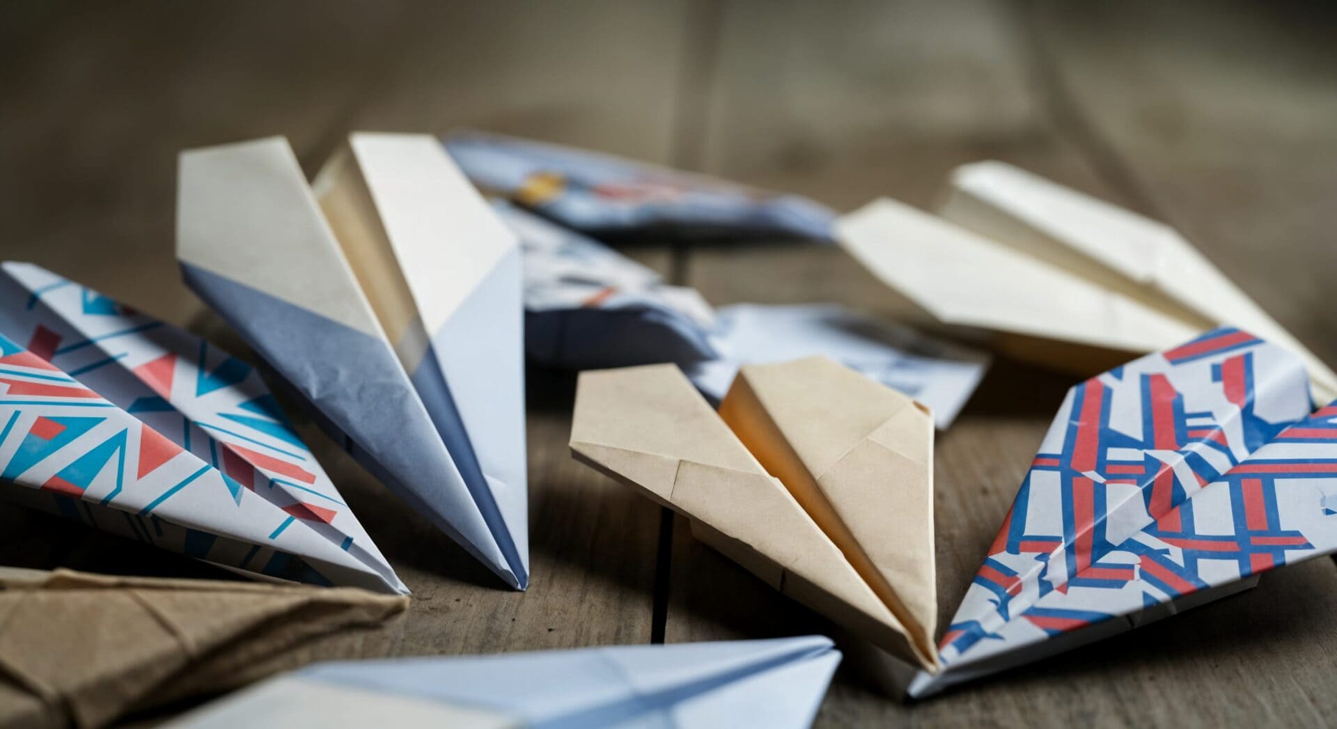 Colorful paper airplanes on wooden surface