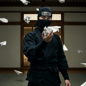 Ninja surrounded by flying paper planes indoors.